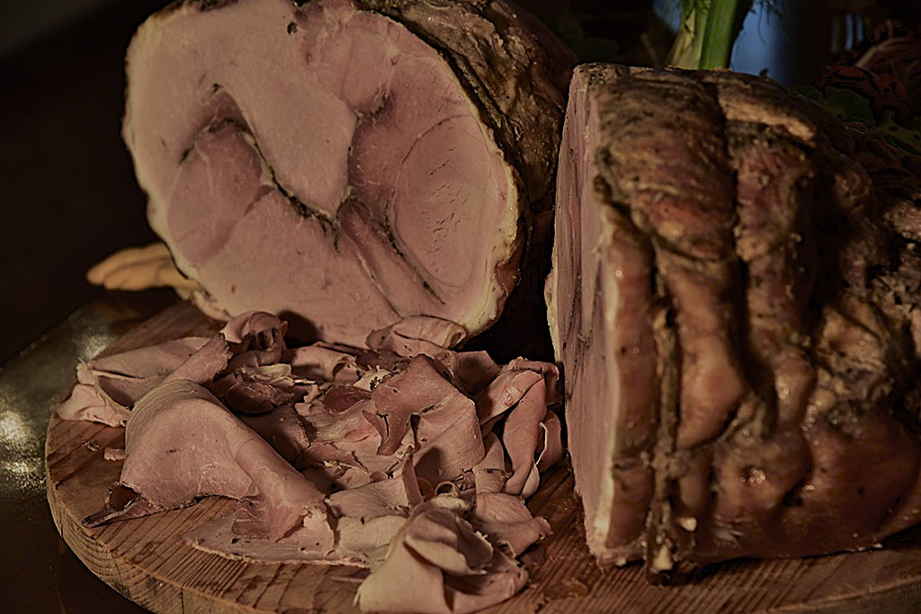 Handwerkliche Porchetta aus Treviso, aufgeschnitten auf einem Holzbrett mit goldbrauner, knuspriger Kruste