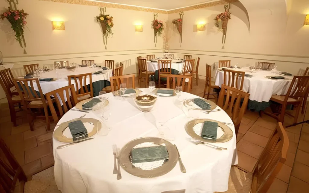 Sala interna del ristorante Andreetta con tavoli apparecchiati per il servizio, decorazioni floreali a parete