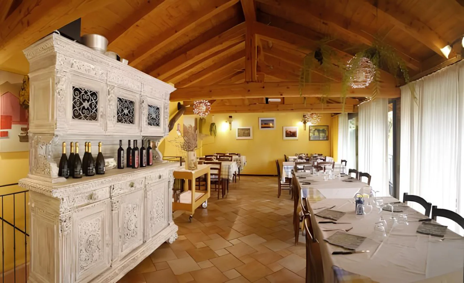Sala da pranzo interna dell'agriturismo Cà Leonilda con travi in legno a vista e tavoli imbanditi